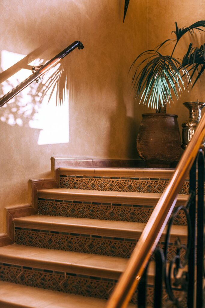Cozy indoor staircase with tiled steps and potted palm, bathed in warm sunlight.