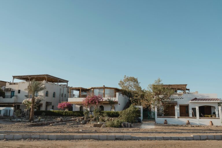 Mediterranean-style villas with pink bougainvillea under a clear blue sky, captured on a sunny day.